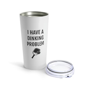 May include: White stainless steel tumbler with a black and white image of a pickleball paddle and ball. The text "I have a dinking problem" is printed on the tumbler.