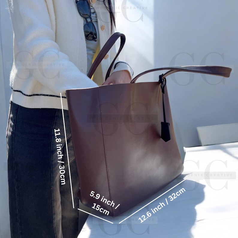 May include: A brown leather tote bag with a top handle and a detachable strap. The bag measures 11.8 inches tall, 12.6 inches wide, and 5.9 inches deep.