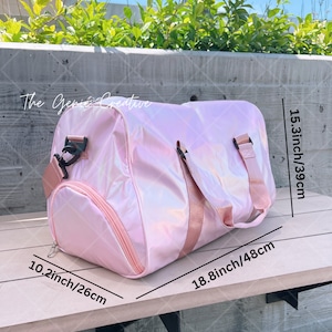 May include: A pink iridescent travel duffel bag with black straps and a zipper closure. The bag measures 10.2 inches by 18.8 inches by 15.3 inches.