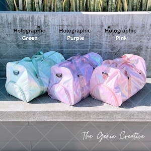 May include: Three holographic duffel bags in green, purple, and pink. The bags are lined up on a concrete surface. The text "Holographic Green", "Holographic Purple", and "Holographic Pink" is above each bag. The text "The Genie Creative" is at the bottom of the image.