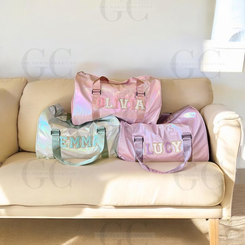 May include: Three iridescent pink duffel bags with personalized names, "Olivia", "Emma", and "Lucy", in colorful letters.