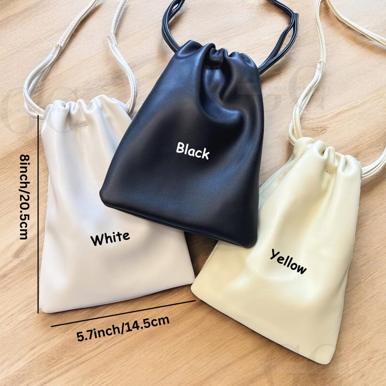 May include: Three small drawstring bags in white, black, and yellow. The bags are 8 inches (20.5cm) tall and 5.7 inches (14.5cm) wide. Each bag has a matching drawstring strap. The word "Black", "White", and "Yellow" are printed on each bag.