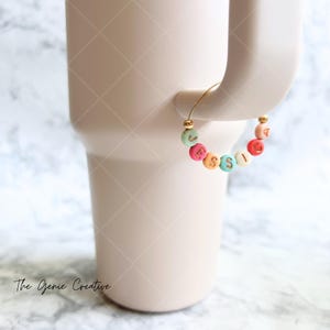 May include: A gold charm bracelet with colorful beads that spell out the name "JESSICA".