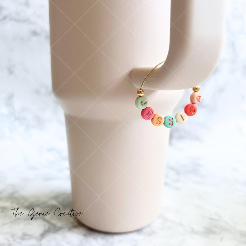 May include: A gold charm bracelet with colorful beads that spell out the name "JESSICA".