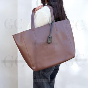 May include: A brown leather tote bag with black straps and a black leather tag that says "M.S."