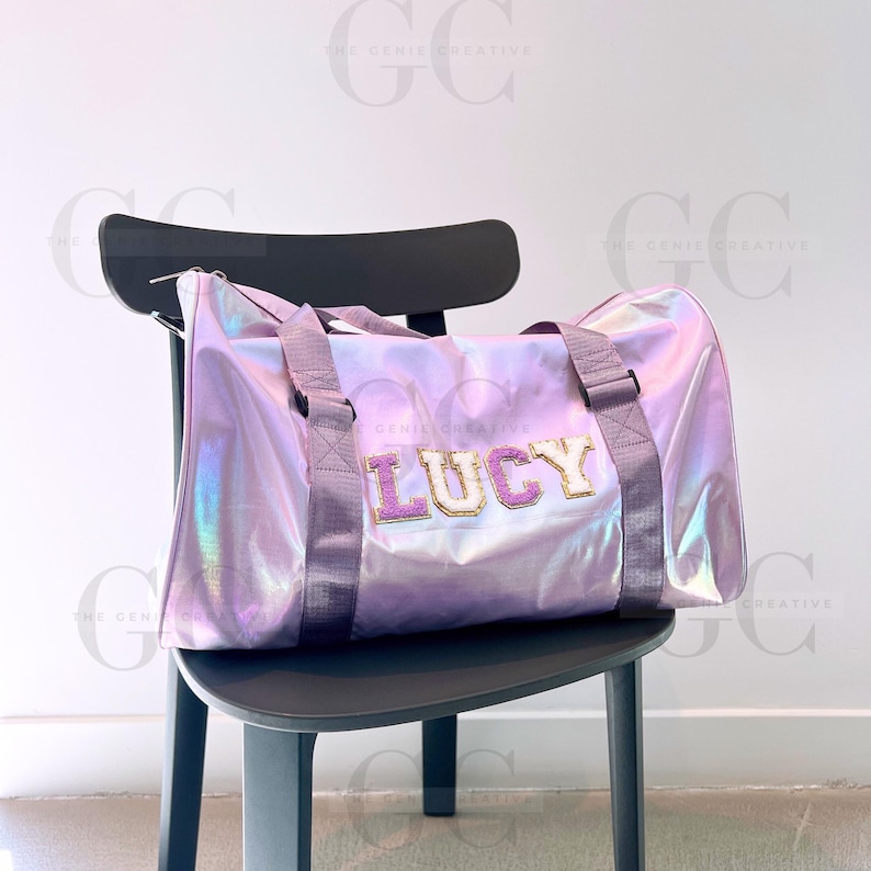May include: A purple iridescent duffel bag with a pink and gold glitter name tag that says "LUCY".