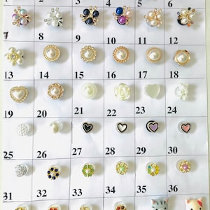 May include: A collection of 42 different decorative embellishments, including hearts, flowers, and animal figures. The embellishments are arranged in a grid pattern on a white background. Each embellishment is numbered from 1 to 42.