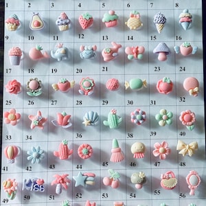 May include: A set of 64 colorful resin buttons with various designs, including hearts, cupcakes, flowers, and animals. The buttons are arranged in a grid on a white background.