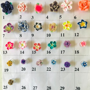May include: Thirty assorted polymer clay flower charms in various colors and styles, including pink, blue, green, white, and yellow. The charms are arranged in rows on a white surface.