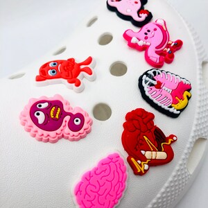 May include: Set of seven colorful anatomical organ charms for shoes. The charms include a brain, heart, lungs, stomach, intestines, and two other organs. The charms are made of a soft, flexible material and are perfect for adding a touch of personality to your shoes.