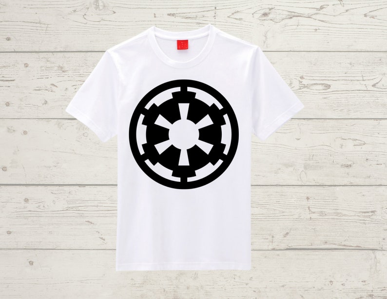 May include: White t-shirt featuring a large black Imperial symbol. The symbol is a circular design with a central circle and radiating shapes. The shirt has short sleeves and a crew neck, suitable for casual wear.