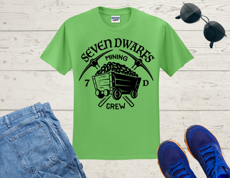 May include: A green t-shirt featuring a black graphic of a mining cart and pickaxes. The text "Seven Dwarves Mining Crew" is printed on the shirt.