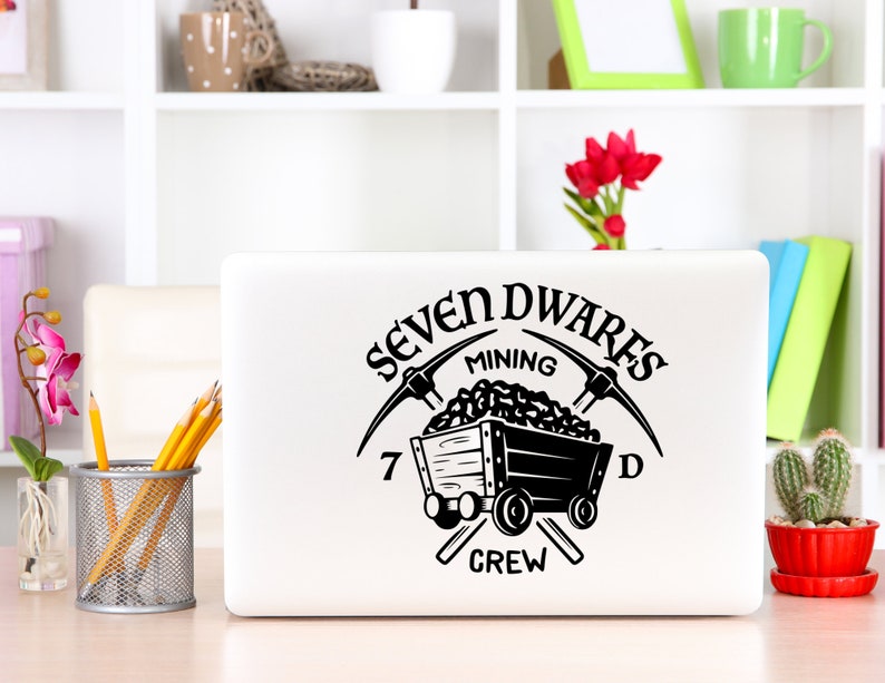 May include: A black and white laptop sticker with the text "Seven Dwarves Mining Crew" and a cartoon image of a mine cart filled with coal and two pickaxes crossed behind it.