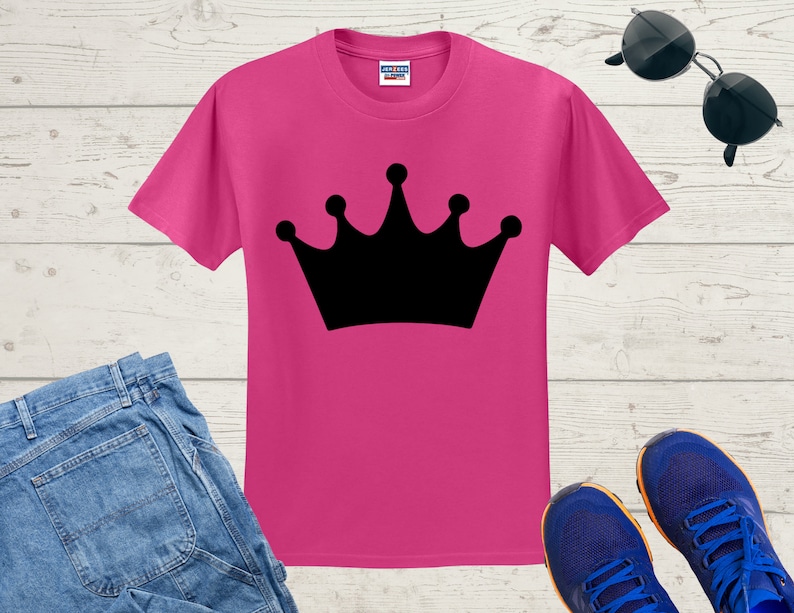 May include: A pink t-shirt with a black crown graphic printed on the front.
