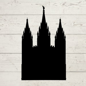 May include: A black silhouette of a temple with three spires, set against a light wood grain background. The central spire is the tallest, topped with a statue. The design is a simple, graphic representation of a religious building.