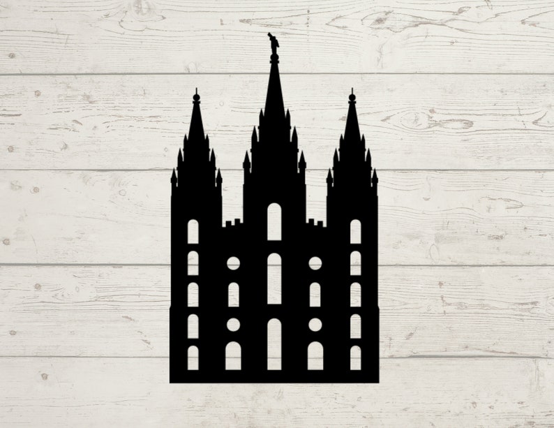 May include: A black silhouette of a cathedral with three spires and multiple arched windows. The building has a detailed design with a small statue atop the central spire. The background is a light wood grain pattern.