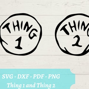 May include: Two black and white circular designs with the text "THING 1" and "THING 2" inside. The designs are on a white wood background.