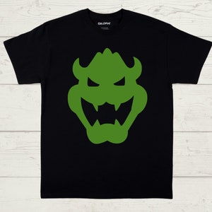 May include: Black t-shirt with a green silhouette of a cartoon monster face.