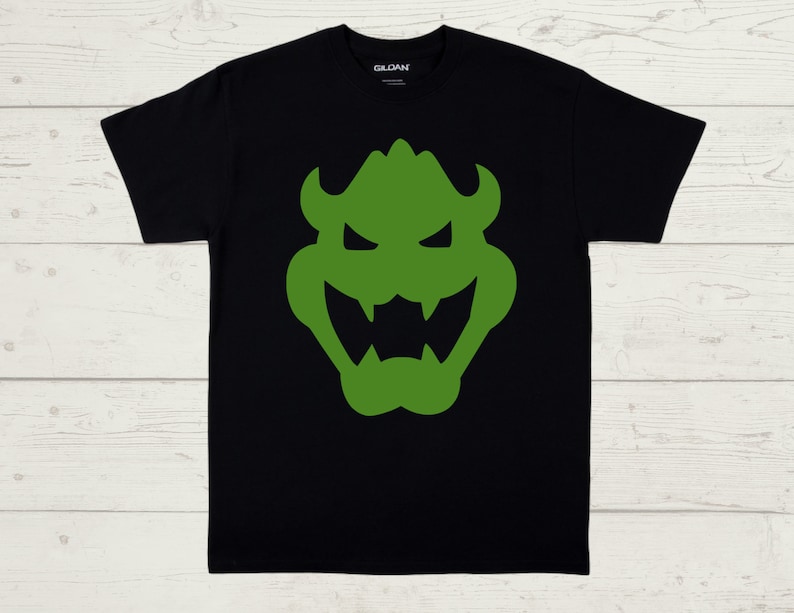 May include: Black t-shirt with a green silhouette of a cartoon monster face.