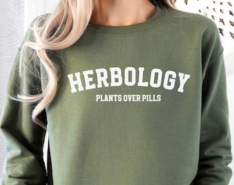 May include: A green sweatshirt with the text "HERBOLOGY PLANTS OVER PILLS" in white.