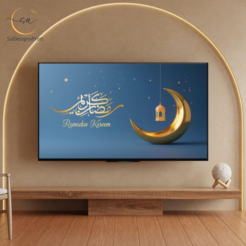 Pu&ograve; includere: Un televisore mostra un design Ramadan Kareem. Il design presenta calligrafia dorata, una luna crescente e una lanterna su sfondo blu. La TV &egrave; sopra una console in legno, con una sfera decorativa a destra.