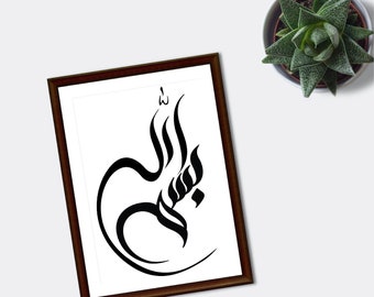 Può includere: Una stampa artistica incorniciata con calligrafia araba nera su sfondo bianco. L'opera d'arte è in una cornice marrone scuro ed è esposta su una superficie bianca. Una piccola pianta succulenta in un vaso bianco è visibile in alto a destra.