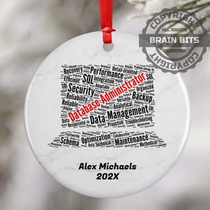 May include: White ceramic ornament with a black word cloud depicting skills and responsibilities of a database administrator. The word "Database Administrator" is highlighted in red. The ornament is personalized with the name "Alex Michaels" and the year "202X".
