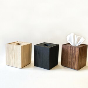 May include: Three wooden tissue box covers in different wood finishes: light wood, black, and dark wood.