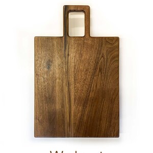 May include: A rectangular walnut wood chopping board with a handle. The handle has a square opening in the centre.