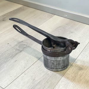 May include: A white ceramic mug with a black handle and the text "But First, Coffee" in a bold, black font. The mug is set against a blurred background, suggesting a cozy setting.