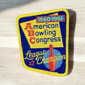 May include: Embroidered patch with a blue background and yellow border. The patch features the text "American Bowling Congress" and "League Champion" with a red bowling pin graphic. The years "1960-1961" are also displayed.