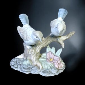 Vintage Porcelain Figurine depicting two birds, often in soft, natural tones, sitting on a branch with floral accents