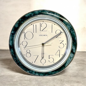 Può includere: Orologio al quarzo rotondo con quadrante color crema e numeri neri. L'orologio ha una lunetta verde effetto marmo e il marchio "VERICHRON" è stampato sul quadrante. Le lancette sono nere e argentate.