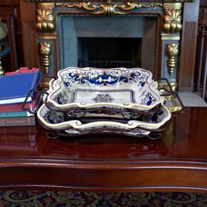 Könnte beinhalten: Ein Set aus drei Keramikbechern mit gesprenkelter, matter Oberfläche. Die Becher sind in den Farbtönen Creme, Hellgrau und Dunkelgrau gehalten. Jeder Becher hat ein schlichtes, modernes Design und einen abgerundeten Henkel.