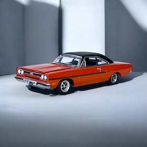 May include: Orange and black classic car model with a black roof. The model car has chrome accents, black racing stripes, and white-walled tires. The car is a vintage model, likely from the 1960s or 1970s.