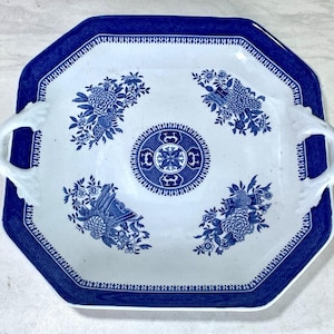 May include: A white and blue octagonal serving platter with floral designs and handles. The platter has a blue border with a geometric pattern and a central medallion. The floral designs are in shades of blue.