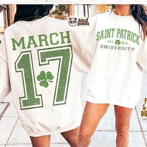 Puede incluir: Una sudadera blanca con un trébol verde y el texto "MARCH 17" en la espalda. La parte delantera de la sudadera tiene el texto "SAINT PATRICK UNIVERSITY EST. 1631" en verde y blanco.