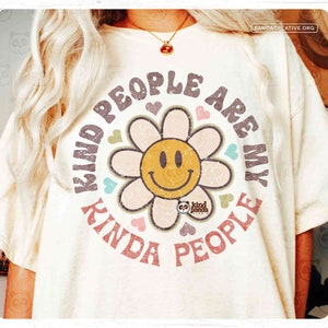 Puede incluir: Una camiseta blanca con un gráfico desgastado de estilo retro que dice "Kind People Are My Kinda People". El gráfico presenta una cara sonriente amarilla dentro de una flor rosa con acentos azules y verdes.