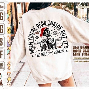 May include: Cream-colored sweatshirt with a graphic featuring a skeleton wearing a Santa hat, with the text "WHEN YOU'RE DEAD INSIDE BUT IT'S THE HOLIDAY SEASON." The design includes snowflakes and stars.