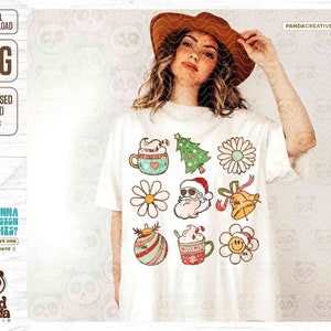 May include: White t-shirt featuring a collection of retro Christmas-themed graphics, including a Santa Claus, Christmas tree, daisy, and a mug with a candy cane. The shirt also has the text "DIGITAL DOWNLOAD PNG".