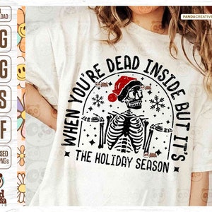 May include: White t-shirt with a distressed graphic of a skeleton wearing a Santa hat. The text reads "When you're dead inside but it's the holiday season." The design includes snowflakes and stars, perfect for the holiday season.