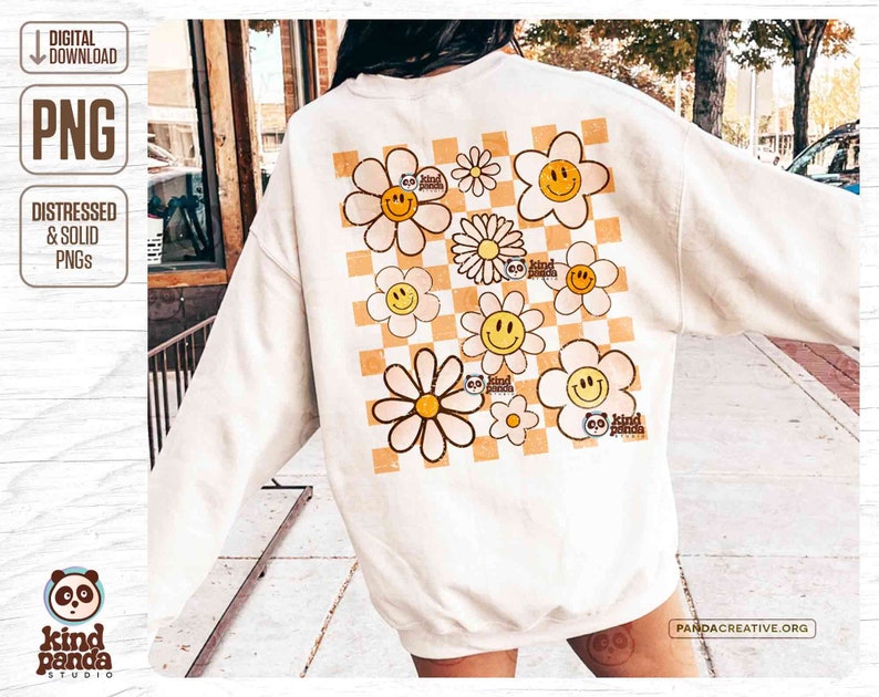 K&ouml;nnte beinhalten: Ein wei&szlig;es Sweatshirt mit einem karierten Muster und gelben G&auml;nsebl&uuml;mchen mit Smiley-Gesichtern. Die G&auml;nsebl&uuml;mchen haben den Text "go kind panda" auf sich.
