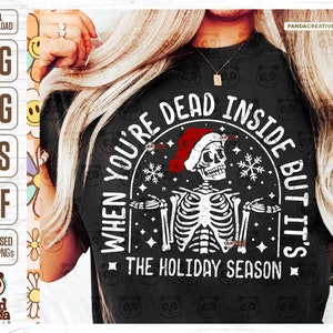May include: Black t-shirt with a distressed graphic of a skeleton wearing a Santa hat. The text reads "WHEN YOU'RE DEAD INSIDE BUT IT'S THE HOLIDAY SEASON". The design includes snowflakes and stars, perfect for the holiday season.