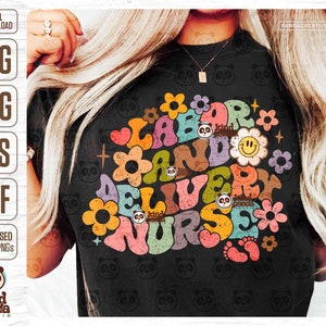 May include: A black t-shirt featuring a colourful graphic design that reads "Labor and Delivery Nurse" in a retro style. The design incorporates flowers, stars and footprints.