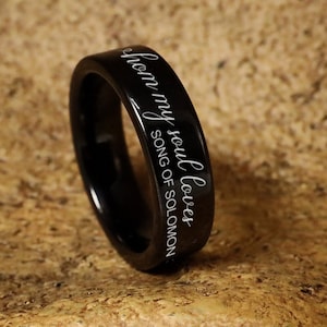 May include: A black tungsten carbide ring with the inscription "I have found the one whom my soul loves" from Song of Solomon 3:4.