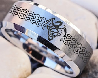 Könnte beinhalten: Ein silberner Ring mit einem keltischen Knotendesign und einem gravierten Drachenkopf auf der Band.