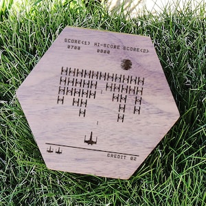 May include: A wooden hexagonal sign with a retro video game design. The sign features a spaceship shooting at enemy spaceships. The text on the sign reads "SCORE<1> 0788 HI-SCORE 0000 SCORE<2> CREDIT 02".