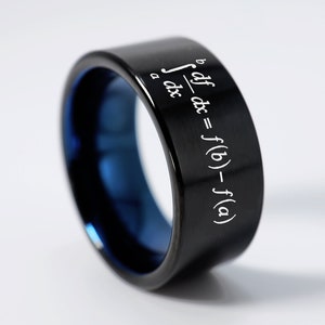 May include: A black and blue tungsten carbide ring with a white inscription of a mathematical formula: "∫_a^b df/dx dx = f(b) - f(a)"