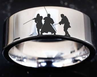 May include: A silver ring featuring a black silhouette of three figures wielding lightsabers. The figures are facing forward and appear to be in a battle stance.