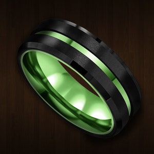 Puede incluir: Un anillo negro y verde con un borde biselado y una incrustación verde. El anillo está hecho de carburo de tungsteno.